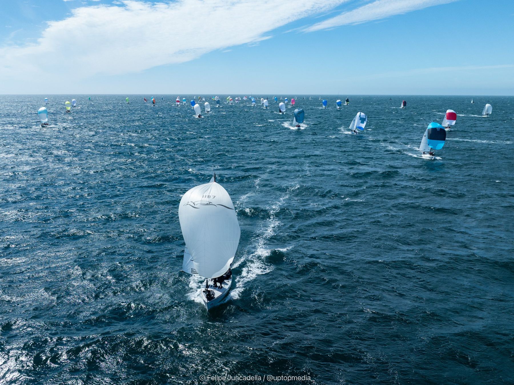 Aerial view of a Moore 24 with a white spinnaker leading boats downwind