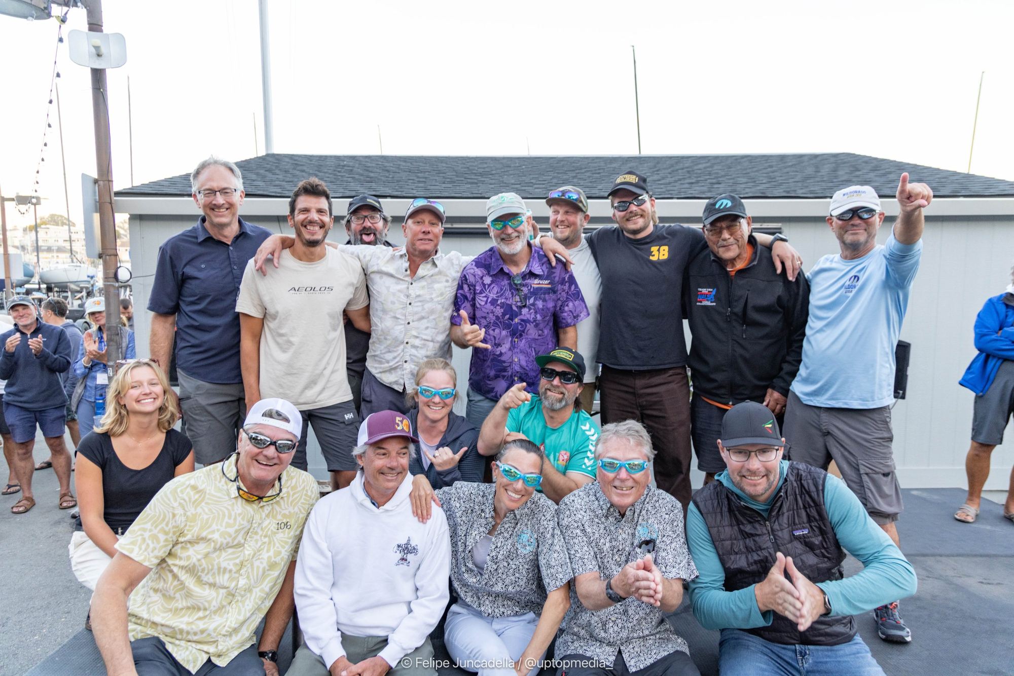 Seventeen sailors who went overboard during the regatta posing together, several wearing swim goggles